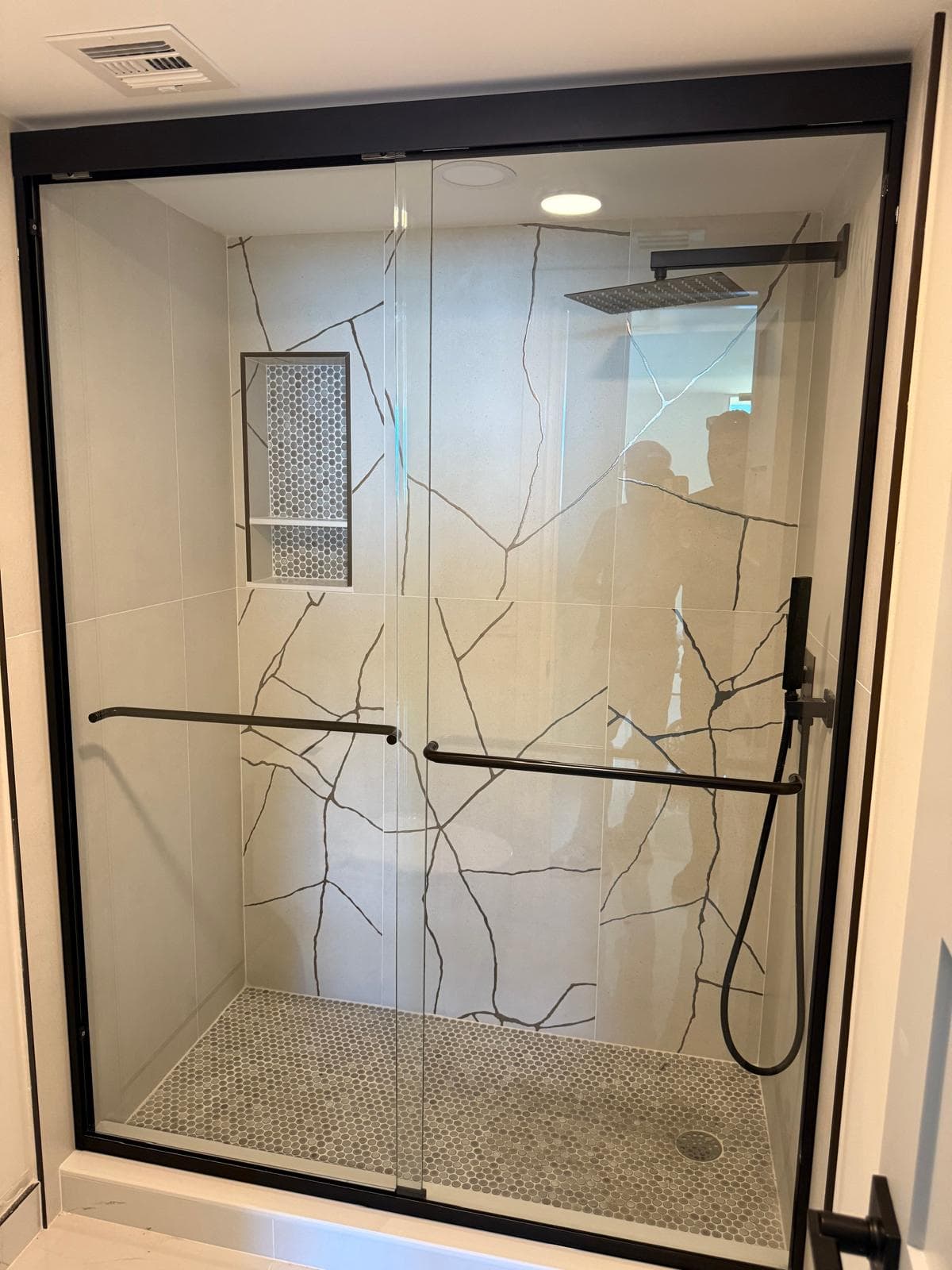 High-quality custom glass shower doors with black hardware, rain shower head, and modern design.