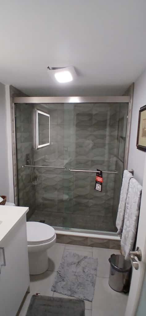 Bright glass shower with modern tiles and safety bars, ideal for luxurious bathroom updates.