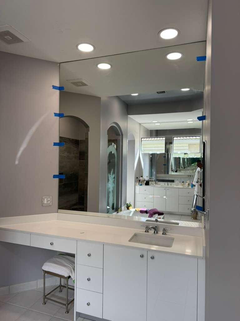 High-quality glass and mirror bathroom vanity installation with modern design and sleek white cabinetry.