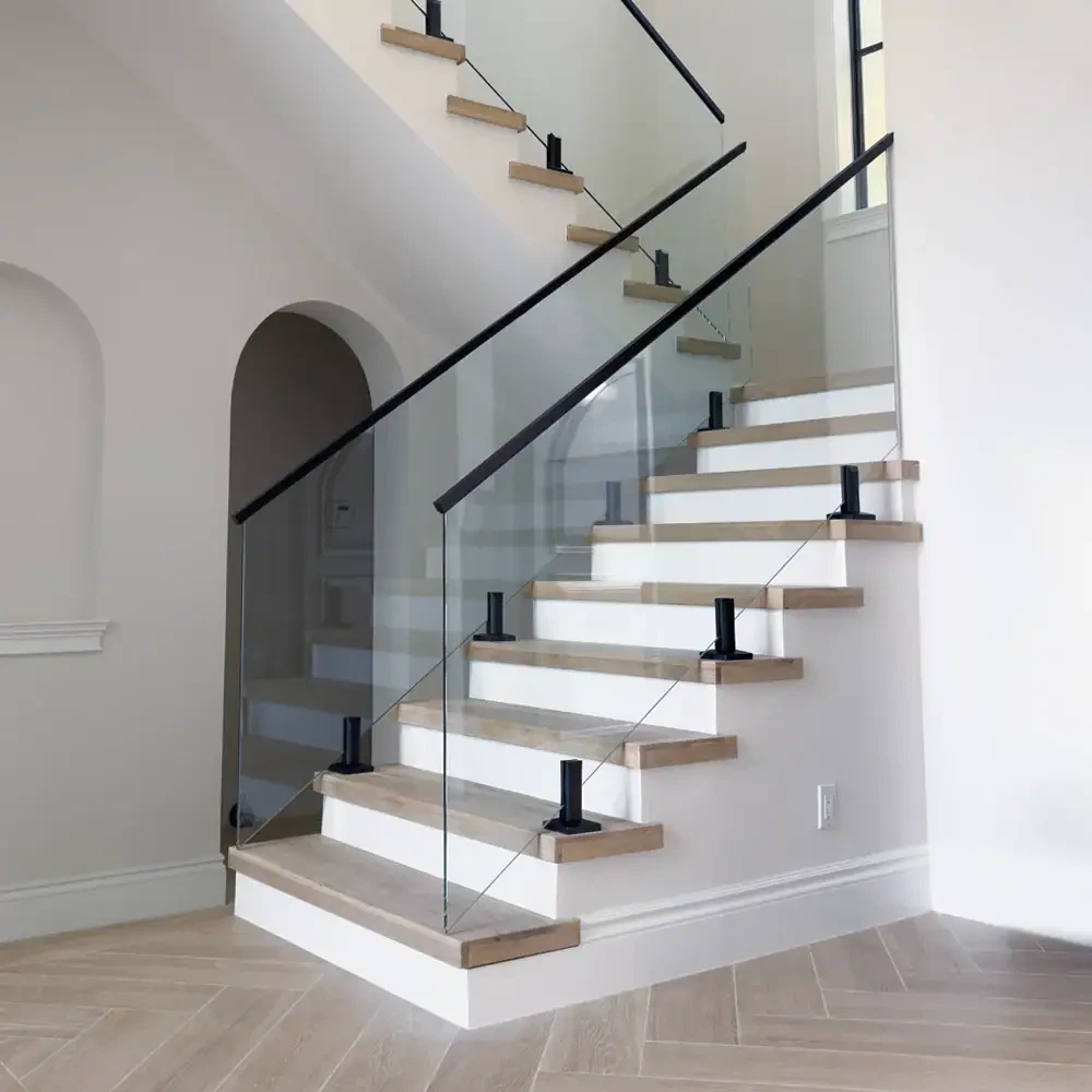Staircase with sleek glass balustrade and wooden steps.