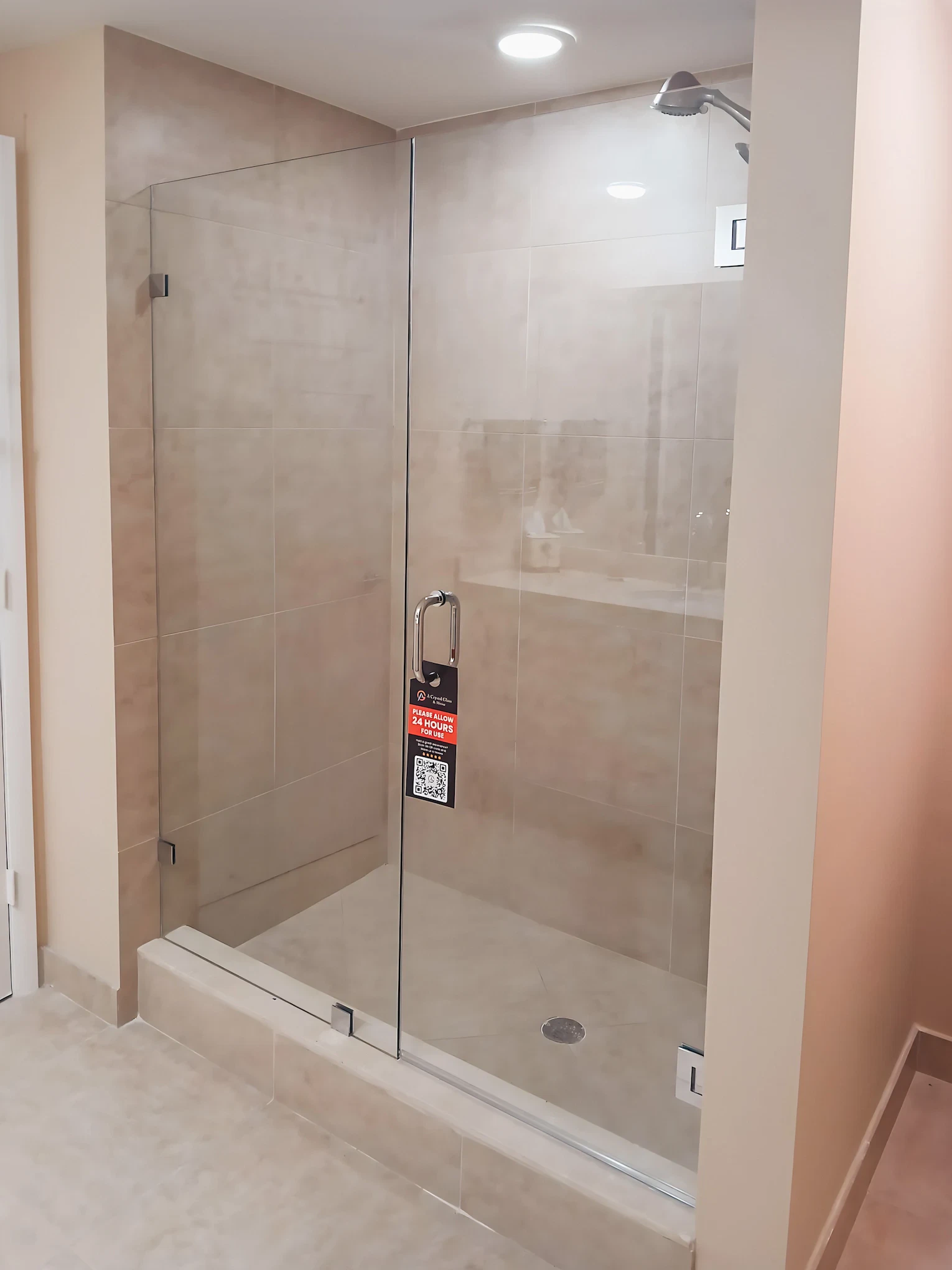 Shower glass door with sleek chrome handle and beige tiled walls.