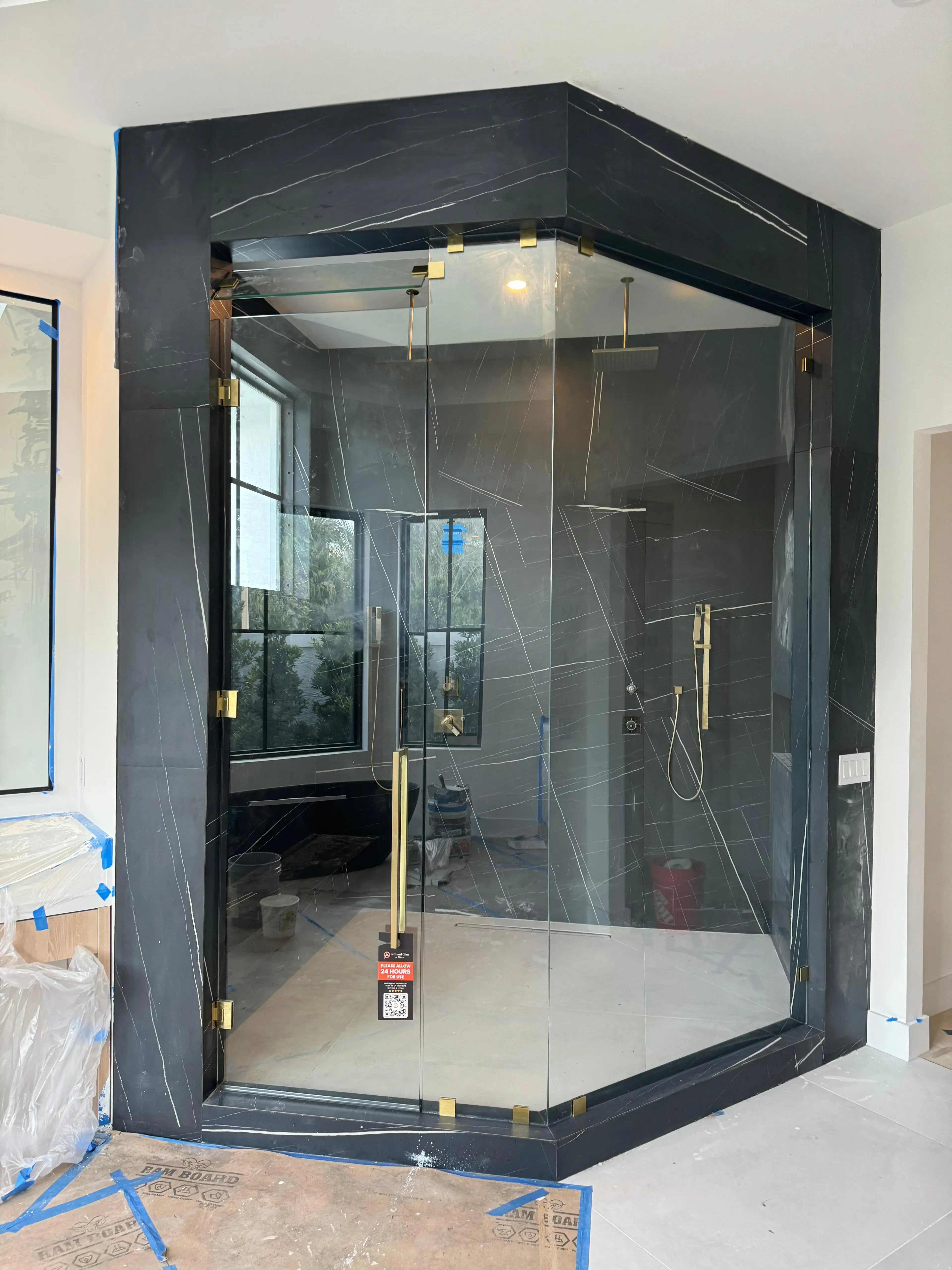 Black marble glass shower enclosure with gold hardware, modern design, durable & elegant.