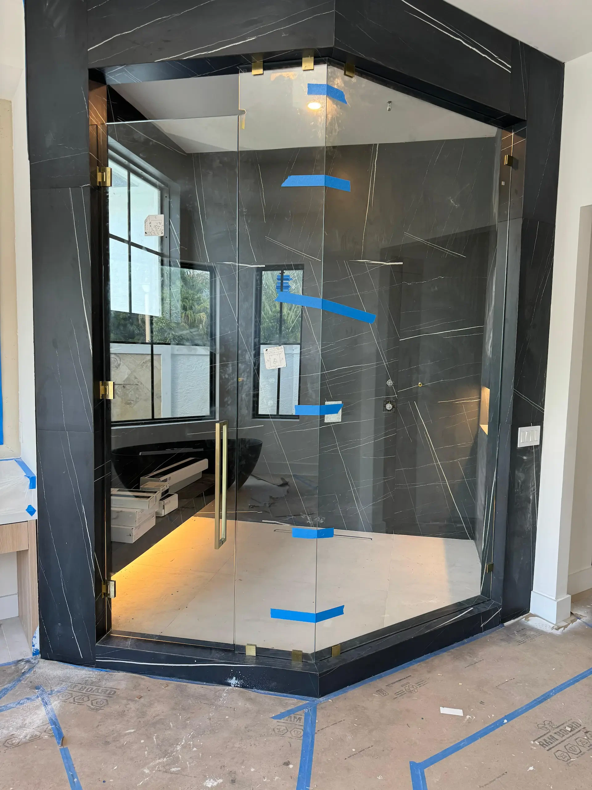High-quality black marble glass shower door with sleek gold hardware, modern design, and custom installation.