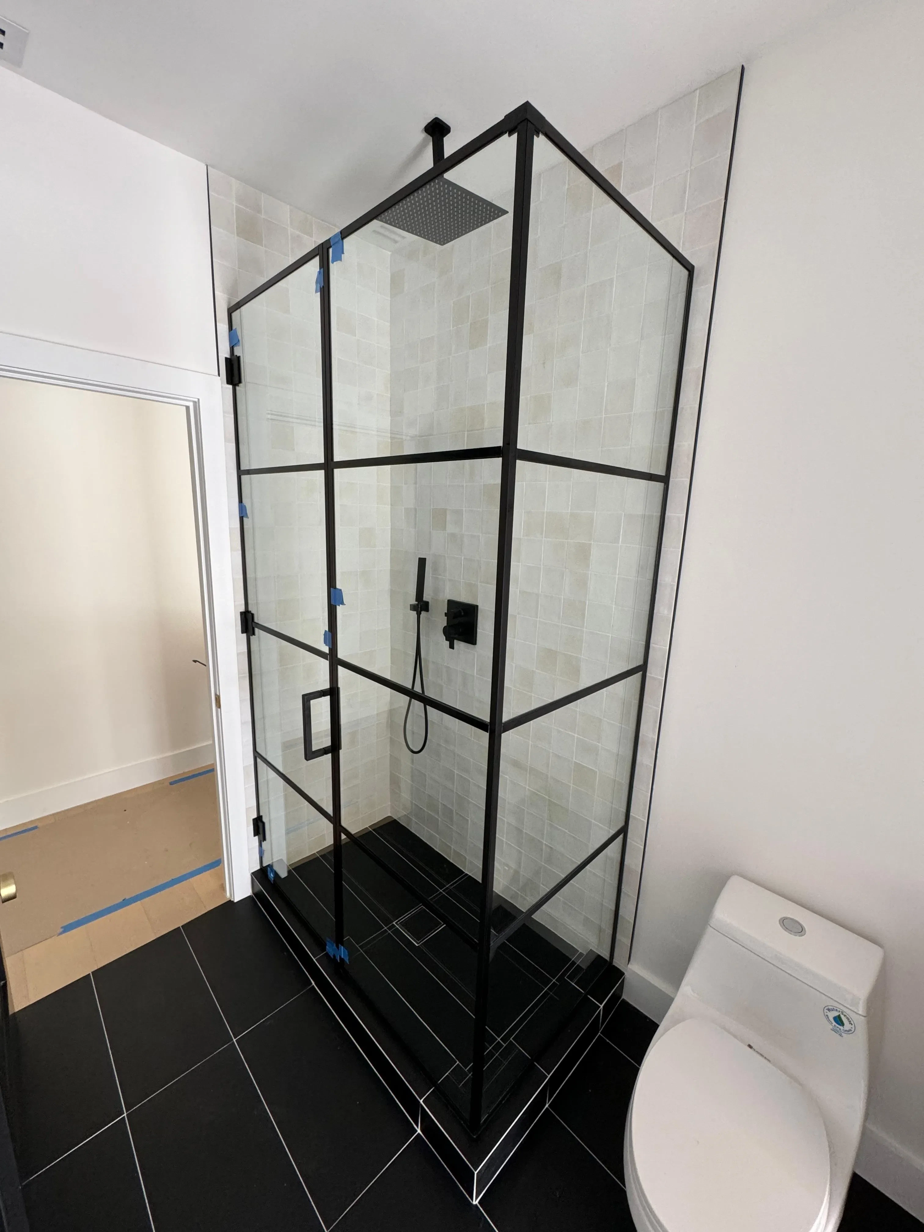 Stunning black metal glass shower enclosure with clear glass panels, modern interior tiles, and rainfall showerhead for a stylish bathroom upgrade.
