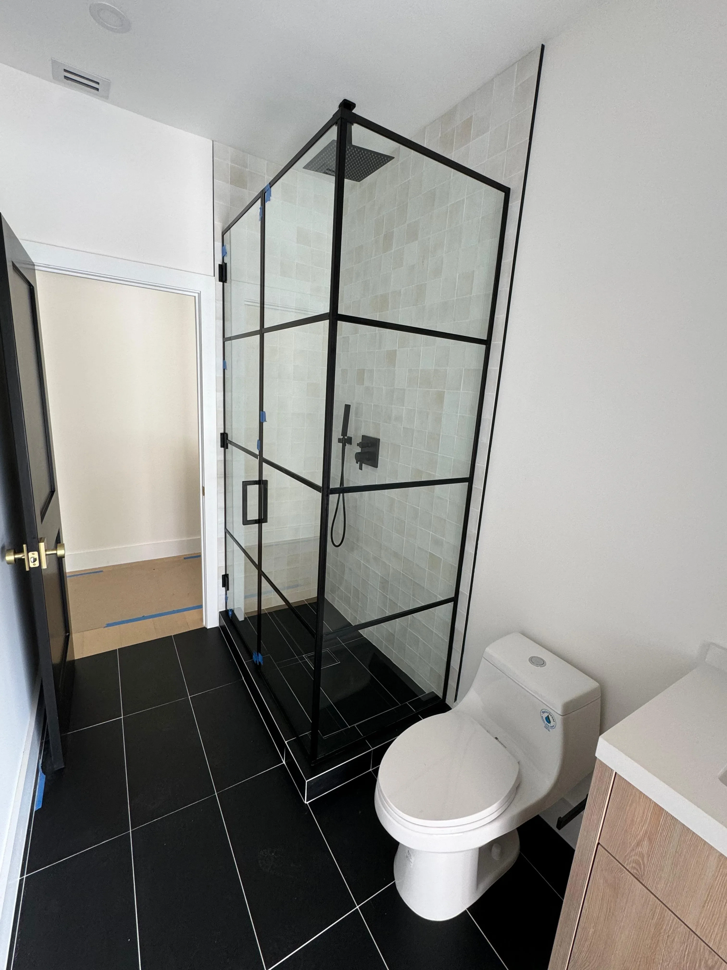 Clear glass shower door with black metal frame, ideal for contemporary bathroom design.
