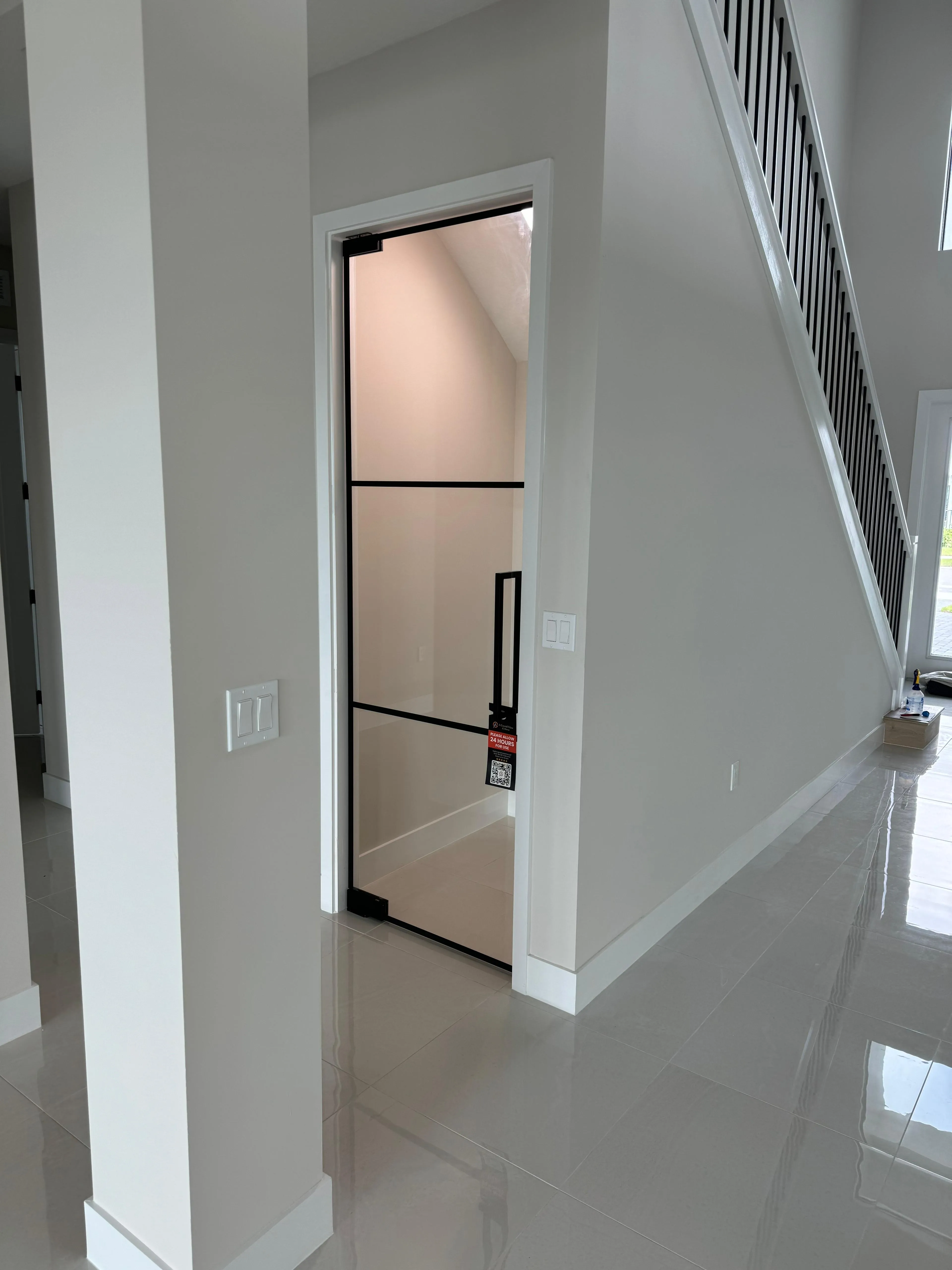 Modern glass elevator door with black trim in a contemporary home interior.