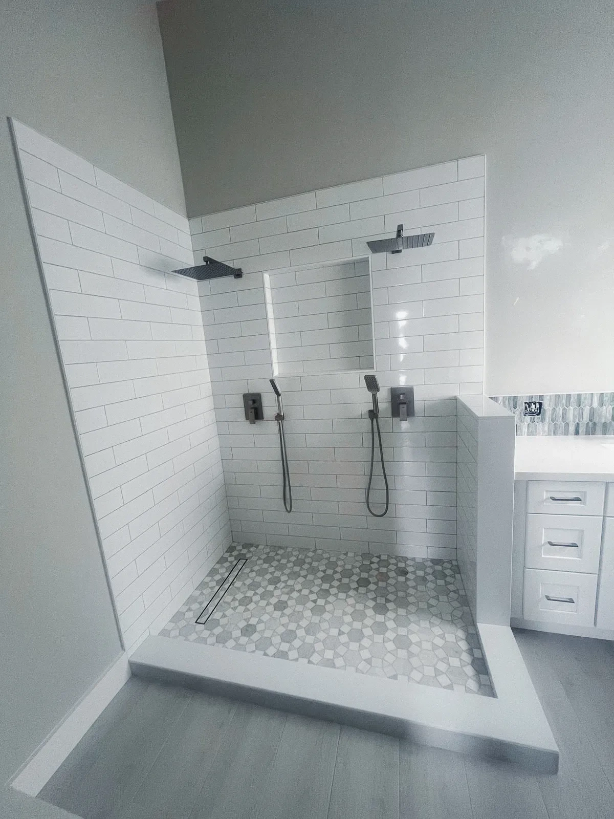 High-quality, frameless glass shower with dual rainfall showerheads in a modern bathroom.