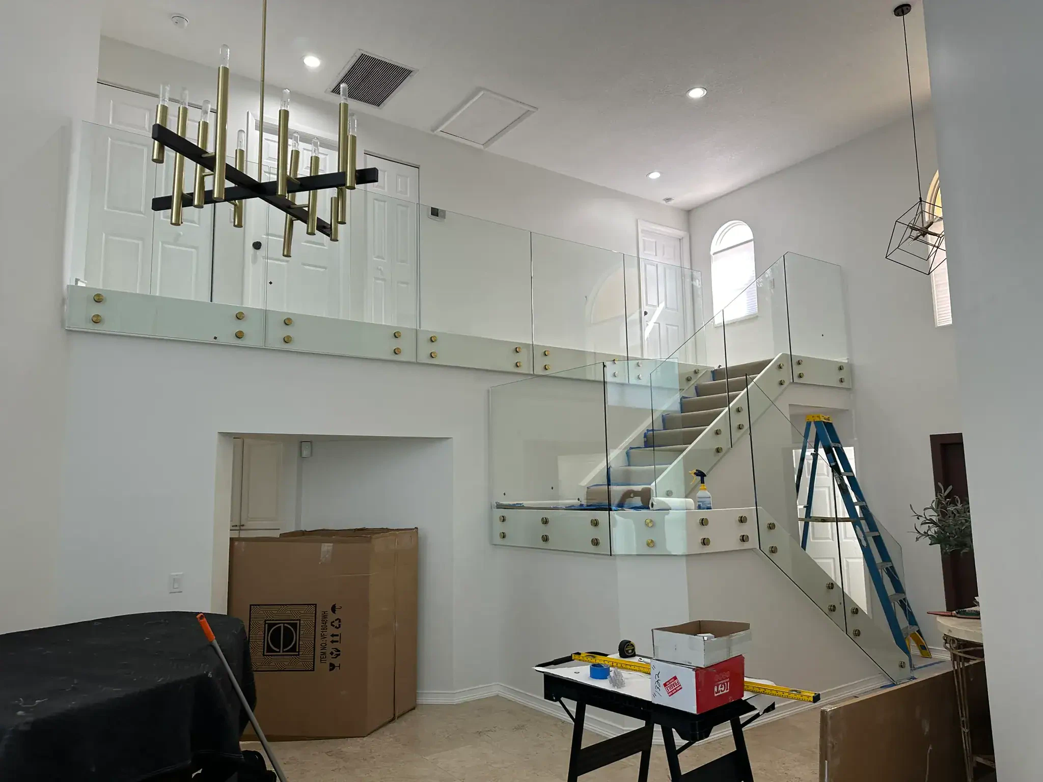 Glass staircase with freestanding glass panels, brass fittings, and contemporary aesthetic.