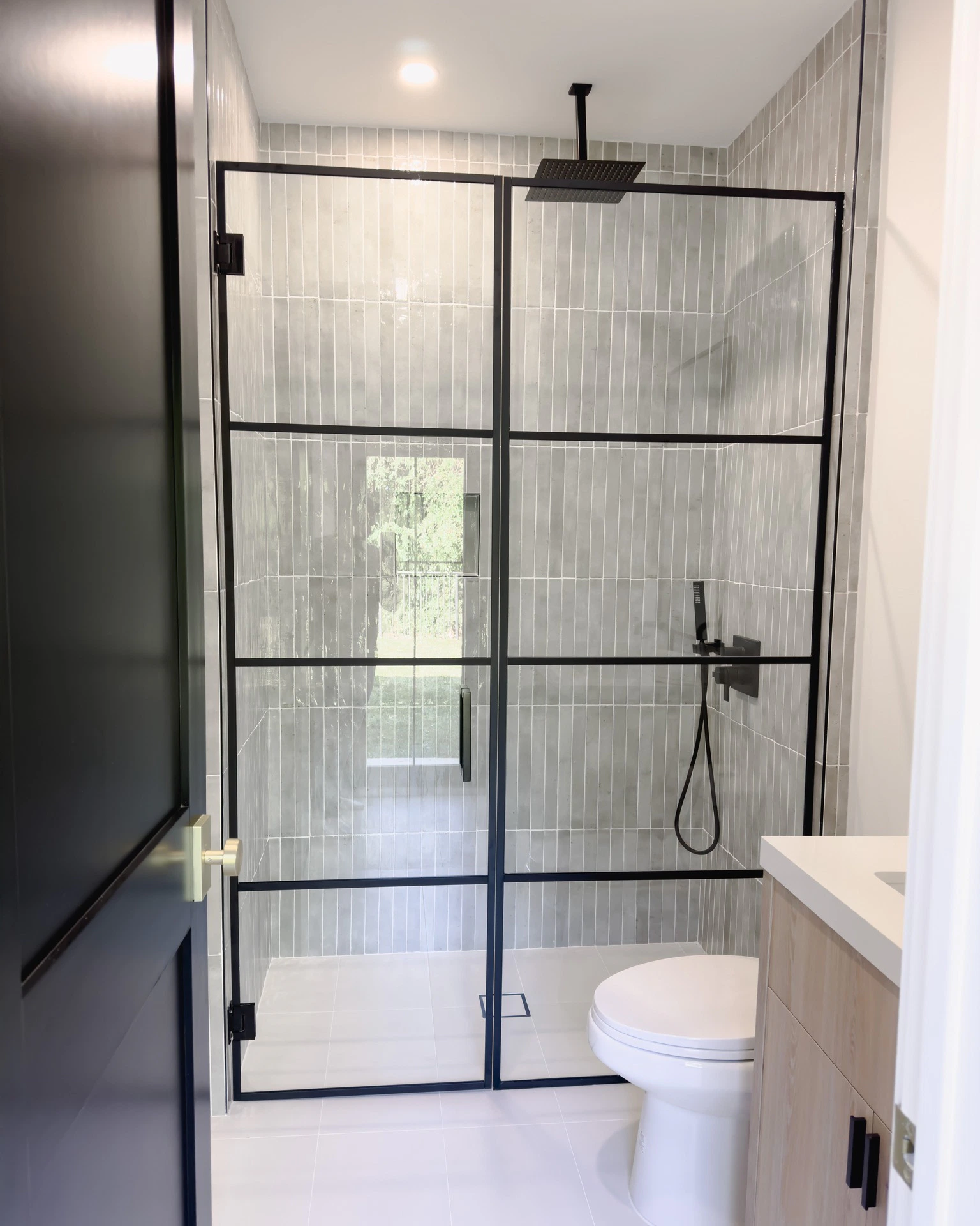 Elegant shower enclosure with black metal framing, glass panels, and contemporary bathroom fixtures.