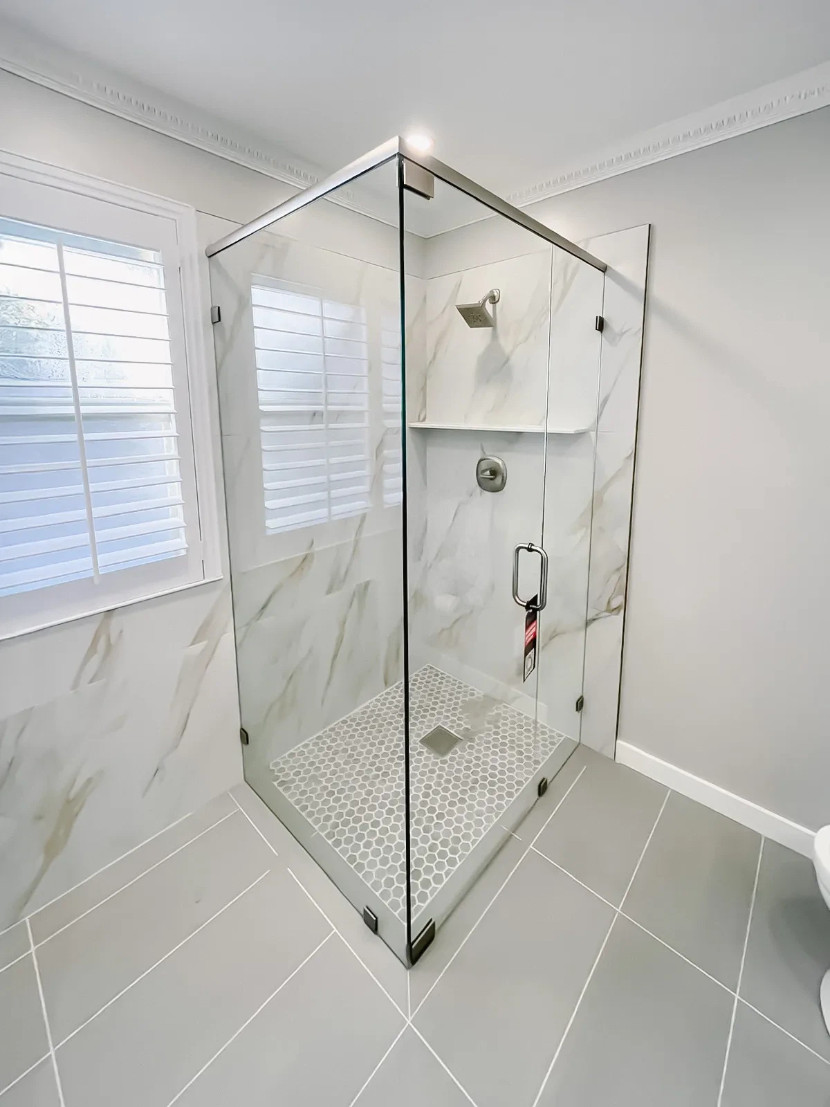 Stainless steel framed glass shower enclosure in modern bathroom.