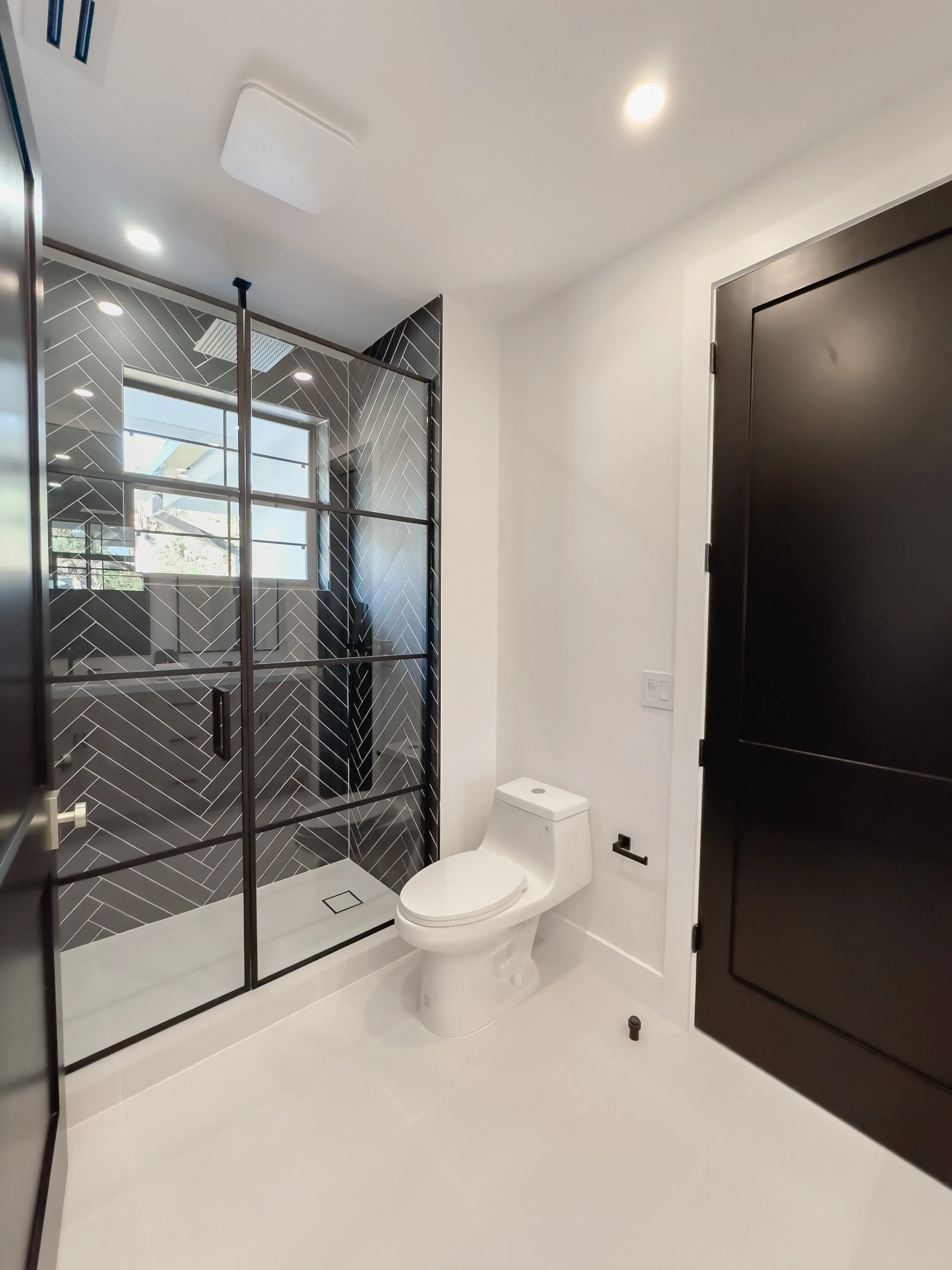 High-quality glass shower enclosure with black frame and herringbone tiled interior for a stylish bathroom upgrade.