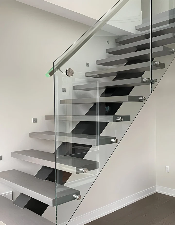 Transparent glass staircase with metal supports, sleek design, ideal for contemporary interiors.