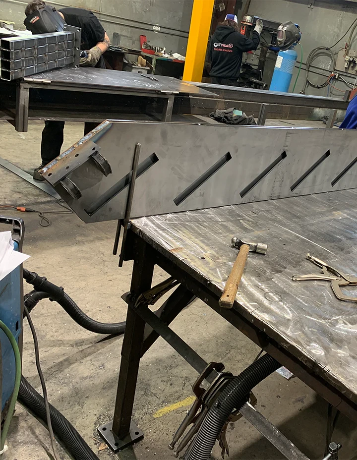Industrial workshop with workers fabricating custom glass and mirrors, tools, and heavy-duty work tables.
