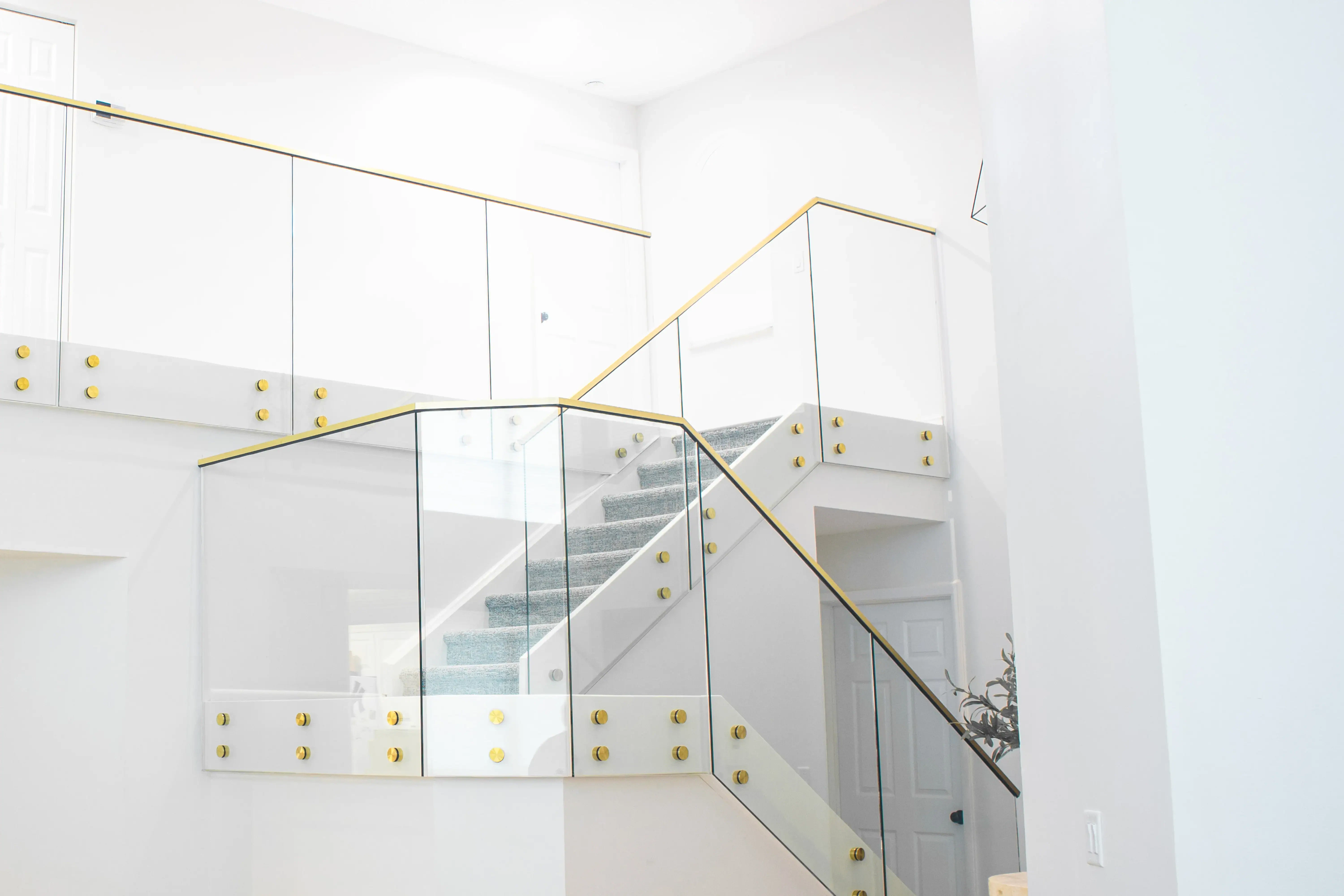 Luxurious glass staircase with sleek gold accents and modern railing design.