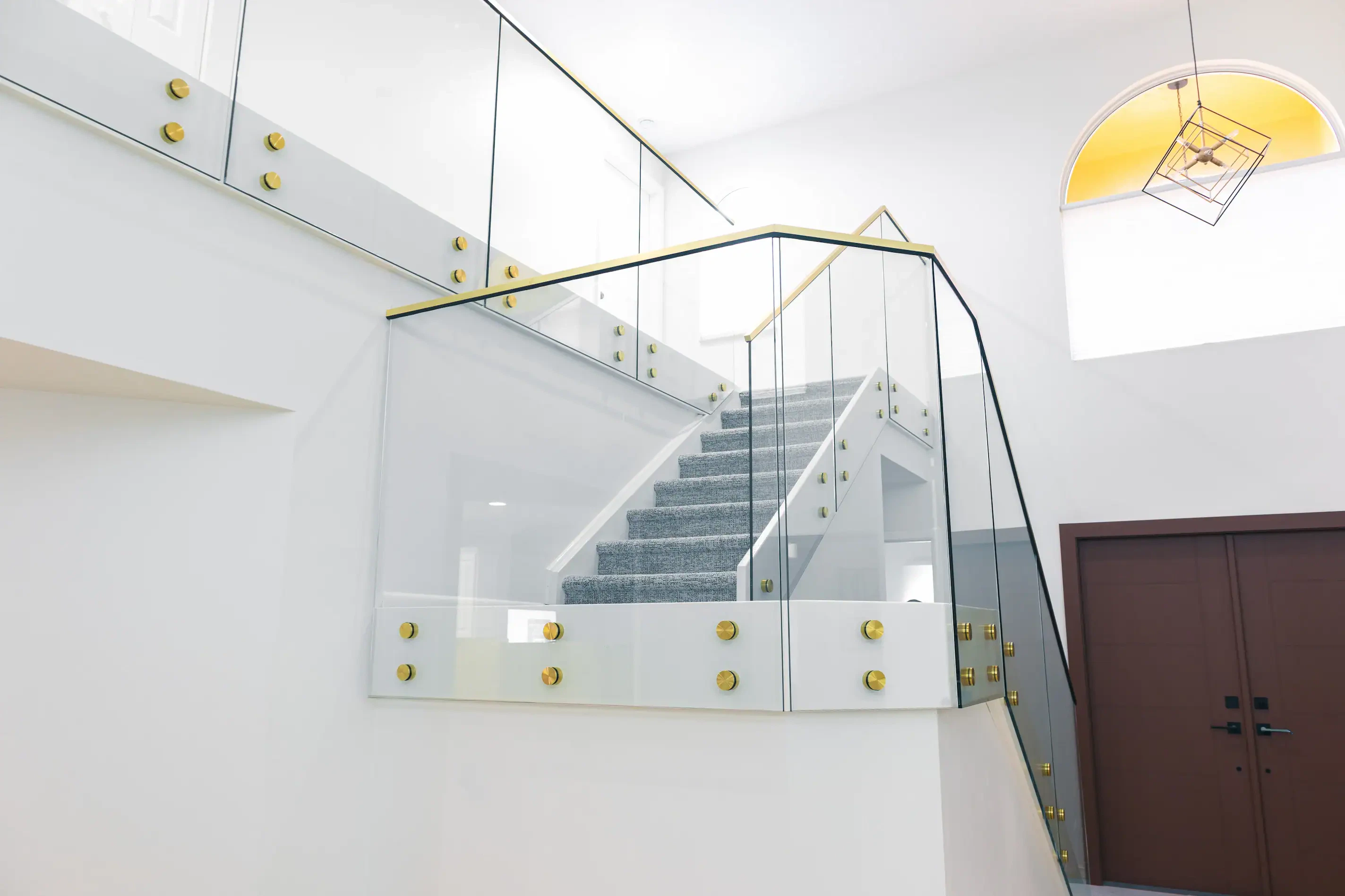 High-quality glass staircase with modern black and gold accents, enhancing contemporary home design.