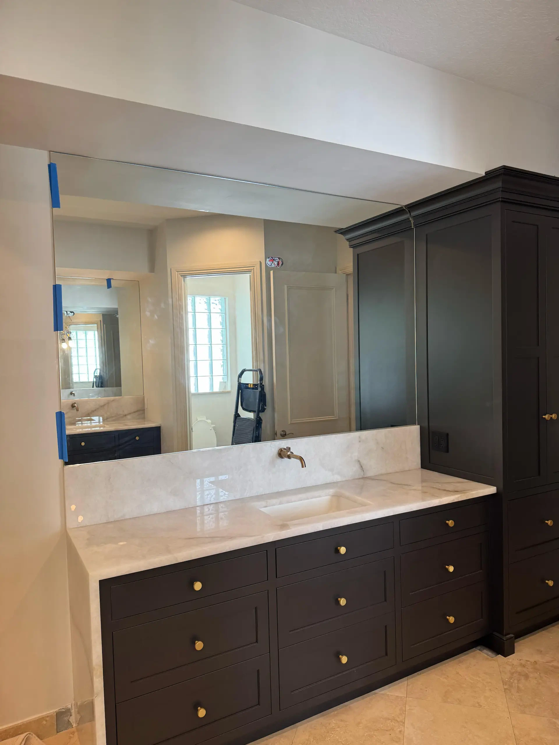 High-quality custom glass mirror reflecting modern bathroom décor and cabinetry.