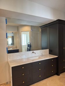 Stunning bathroom mirror and black cabinetry with gold accents in a modern bathroom design.