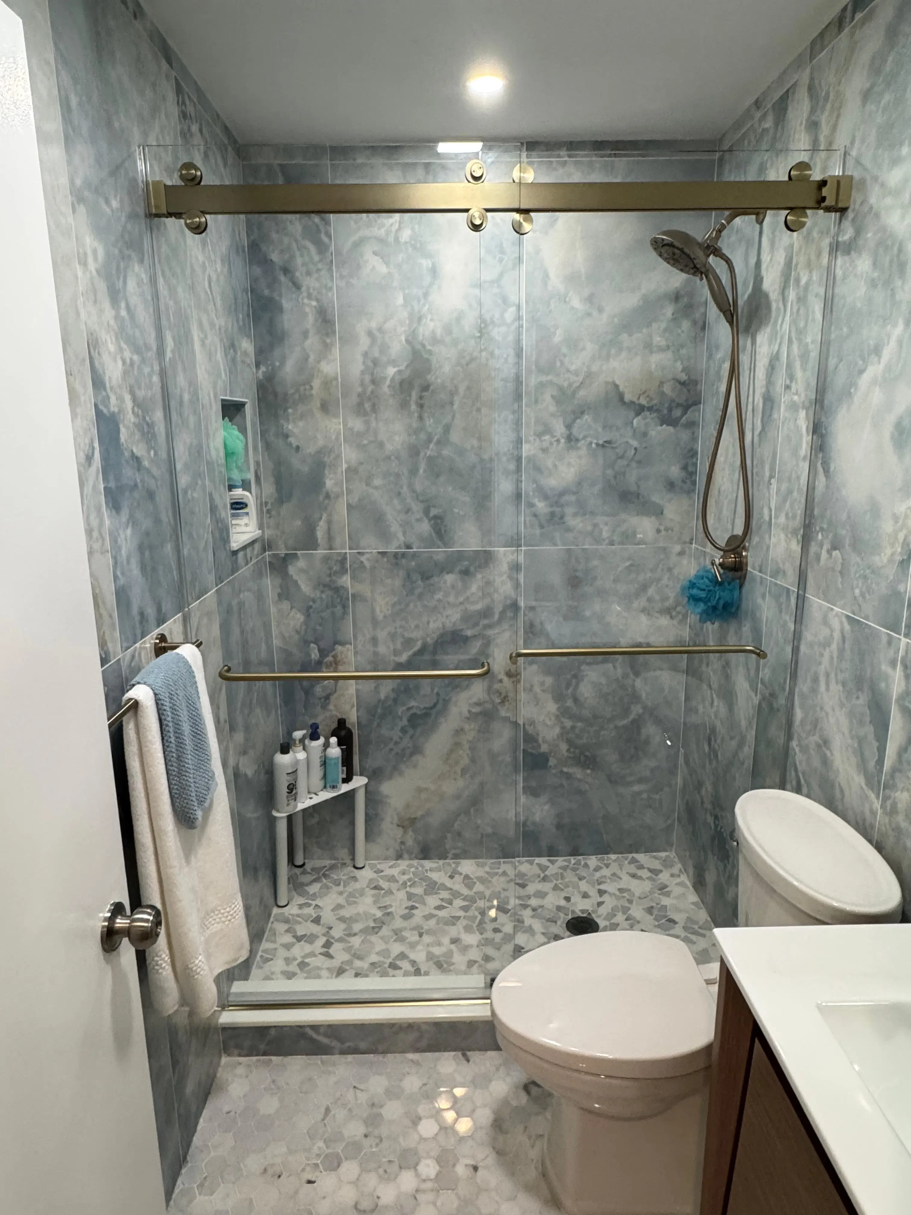 High-quality glass shower with sleek hardware and marble wall tiles for a luxurious bathroom look.