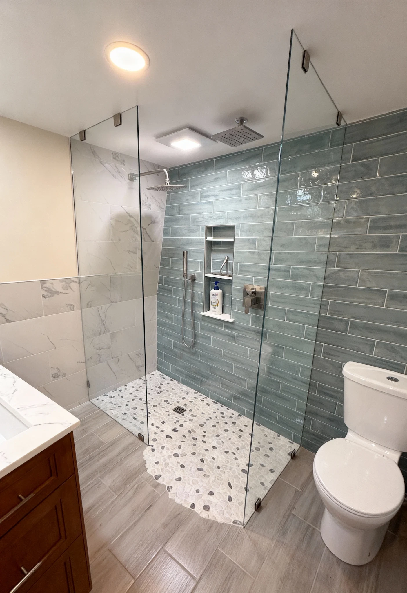 Sturdy frameless glass shower enclosure with modern green tile accents.