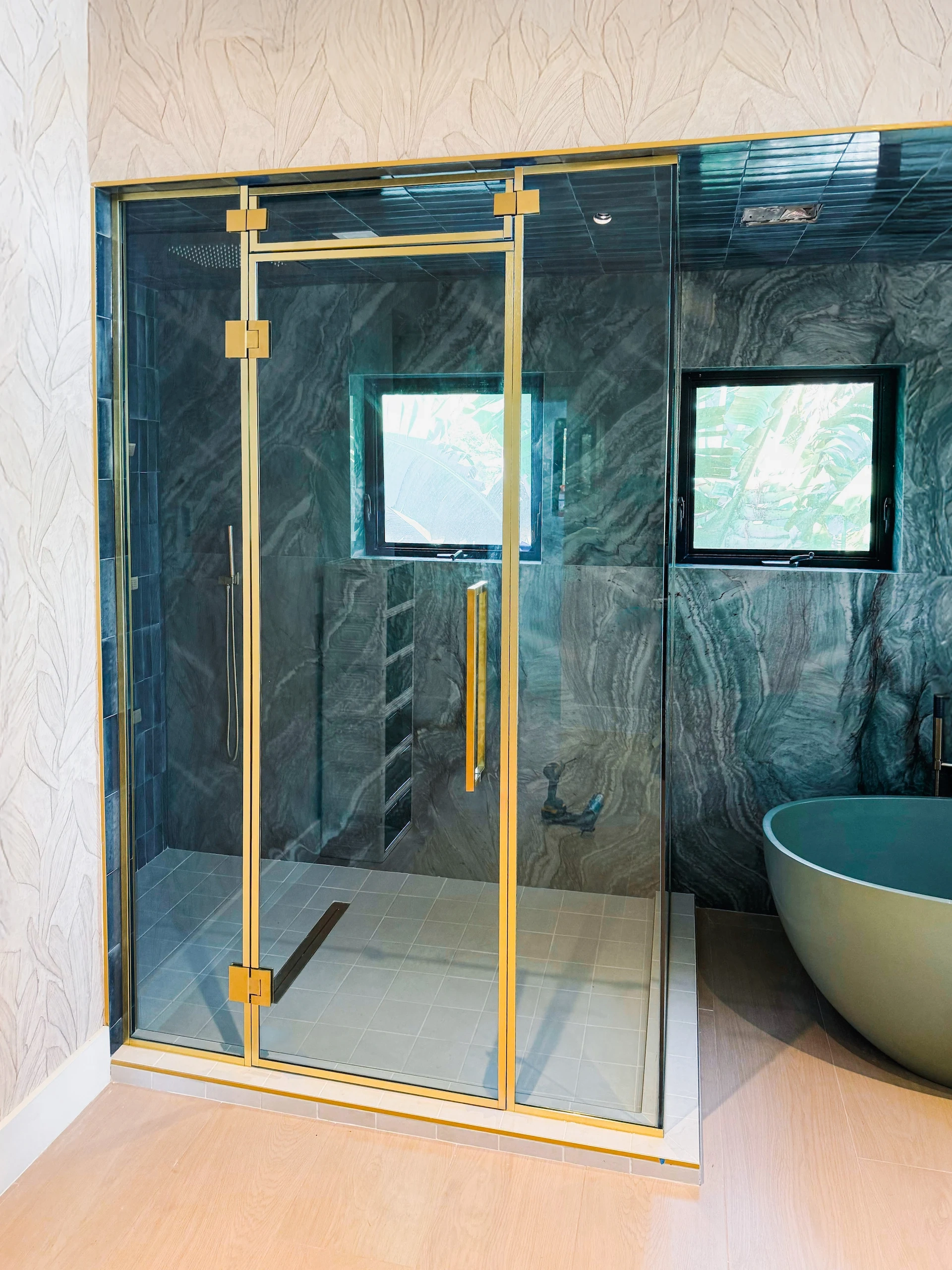 Versatile glass shower with gold frame in modern bathroom setting.