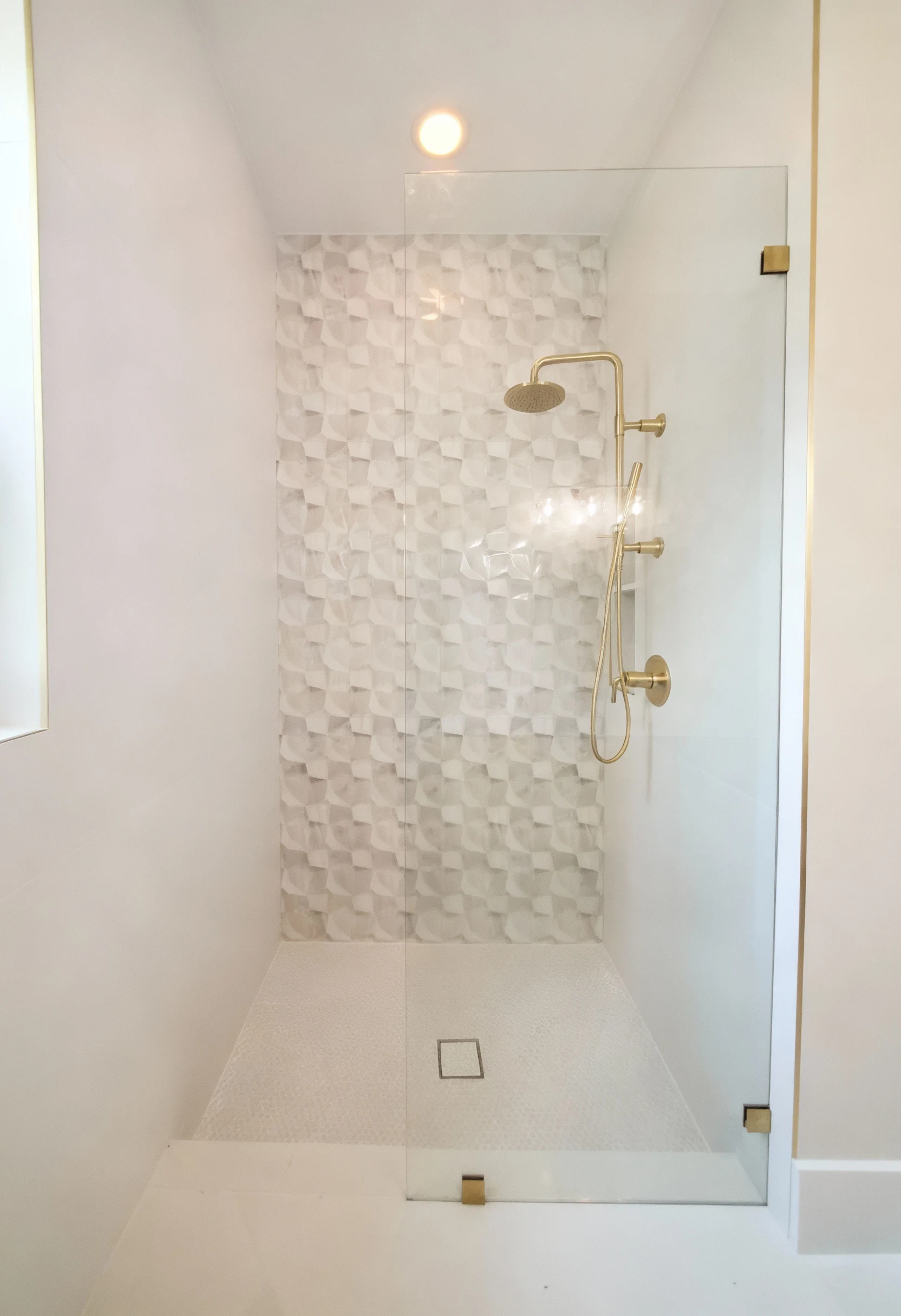 High-quality glass shower enclosure featuring gold fixtures and textured interior tiles for modern bathroom design.