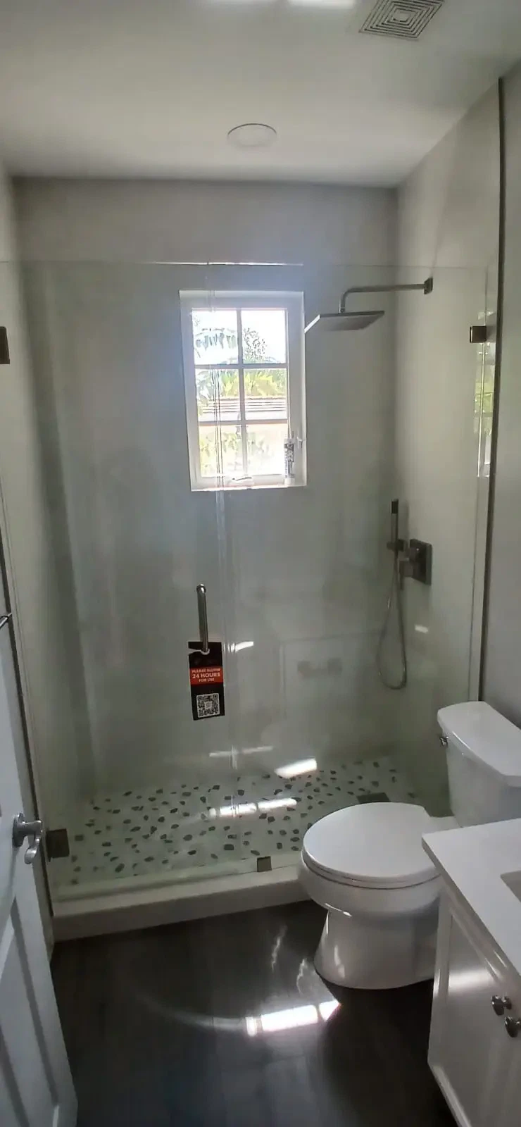 Bright bathroom featuring a sleek glass shower with a window for natural light and contemporary fixtures.
