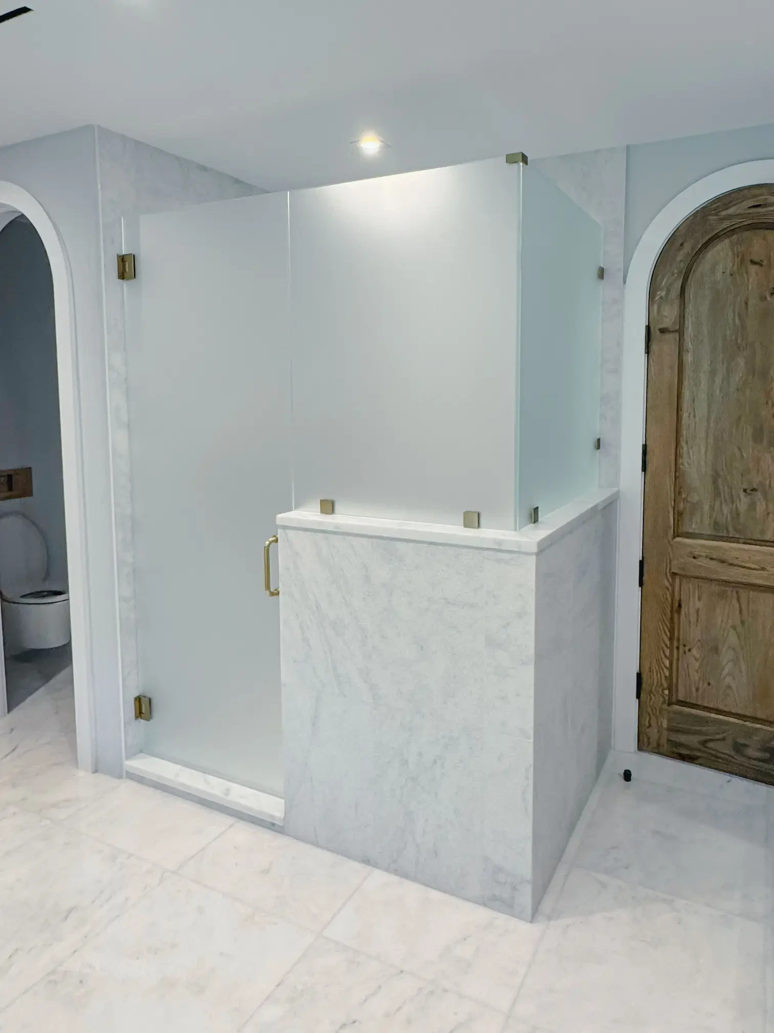 Clear glass shower with brass handle, modern bathroom design, high-quality glass, elegant fixtures.