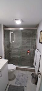Bright glass shower with modern tiles and safety bars, ideal for luxurious bathroom updates.