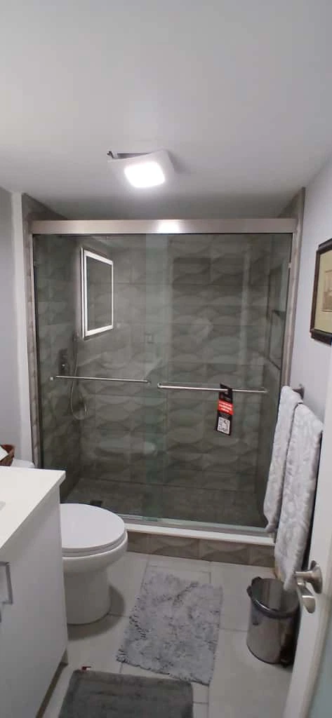 Bright glass shower with modern tiles and safety bars, ideal for luxurious bathroom updates.