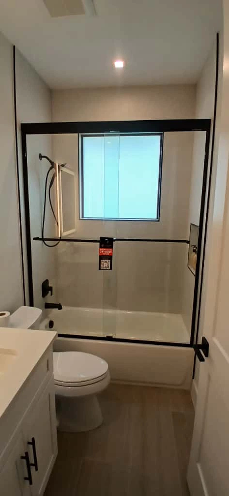 Clear glass shower door with black frame and hardware.