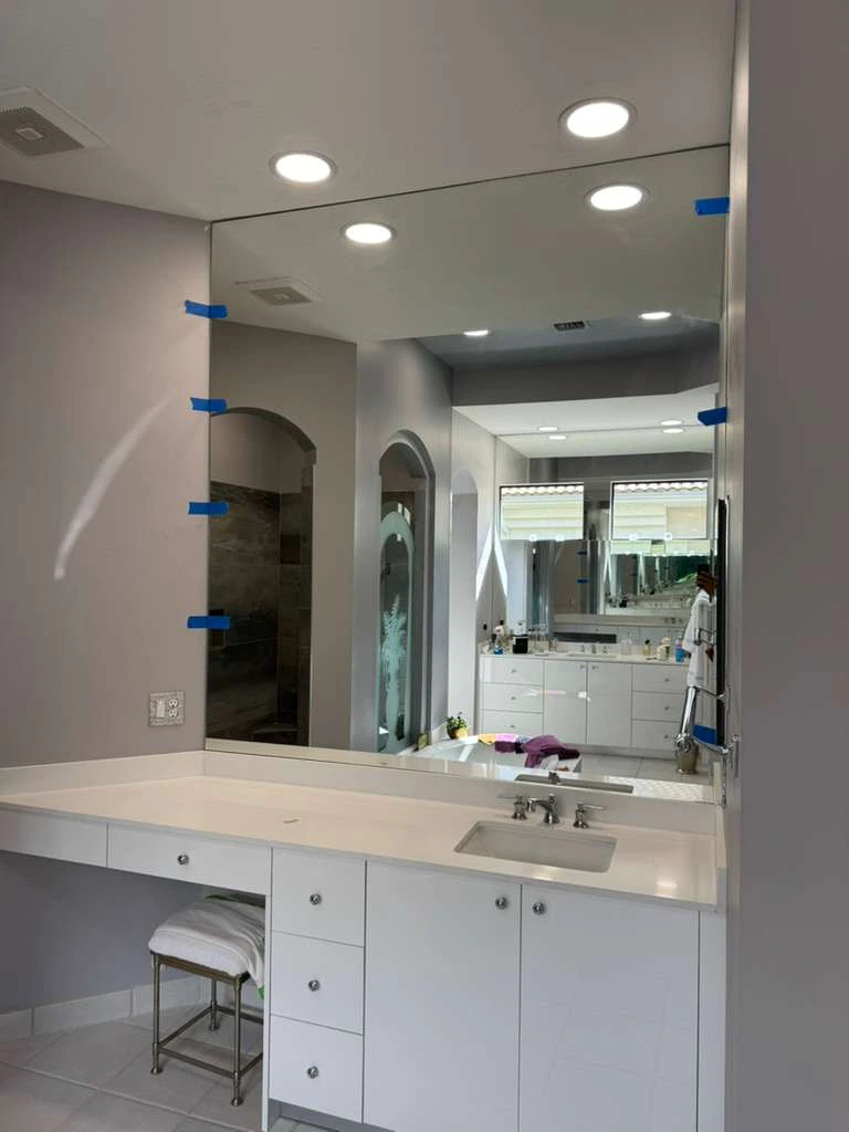 High-quality glass and mirror bathroom vanity installation with modern design and sleek white cabinetry.