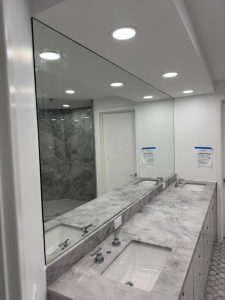 Large decorative mirror in bathroom with marble countertop and double sinks.