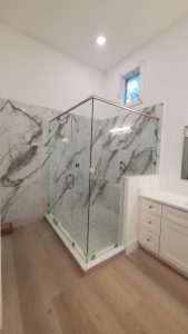 Custom glass shower enclosure featuring clear frameless glass and marble walls for luxury bathrooms.