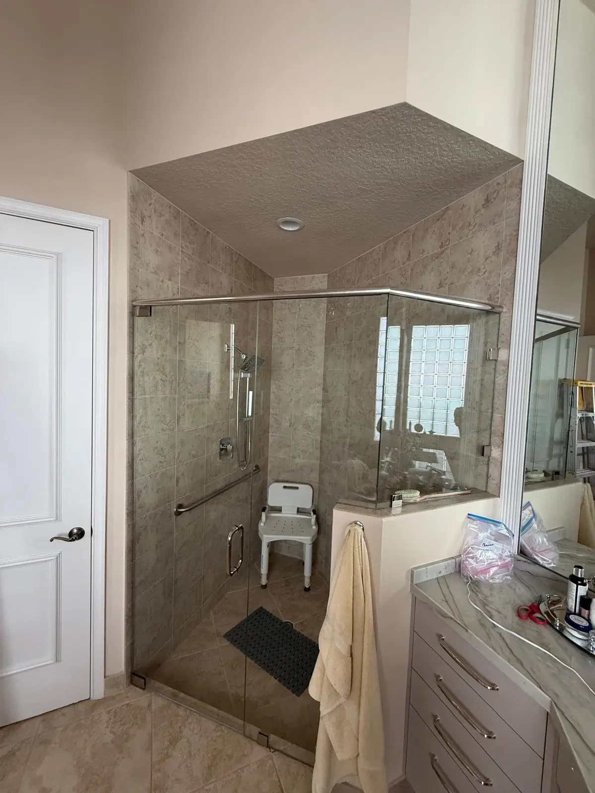 Bright, modern bathroom with custom glass shower door and marble accents.