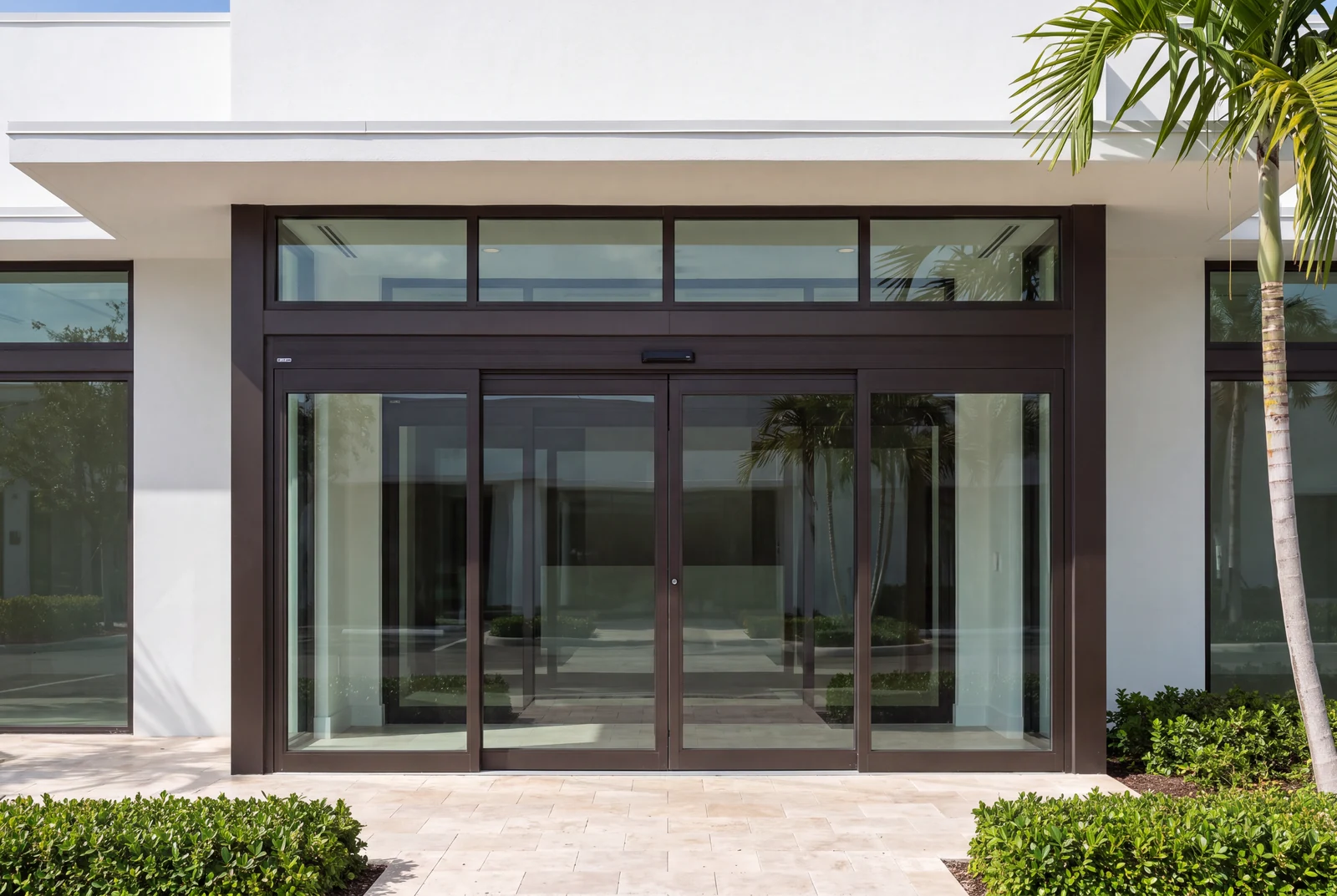 Commercial entrance with automatic sliding glass doors, sidelites and a transom in a dark bronze aluminum storefront