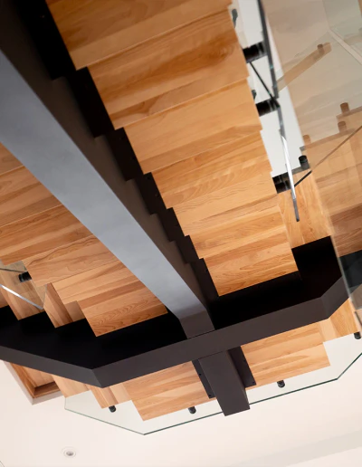 Elegant wooden staircase featuring glass panels and black metal accents, perfect for contemporary interiors.