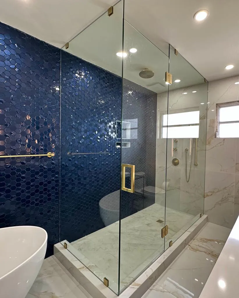High-quality glass shower enclosure with gold hardware and stylish blue mosaic tile wall.