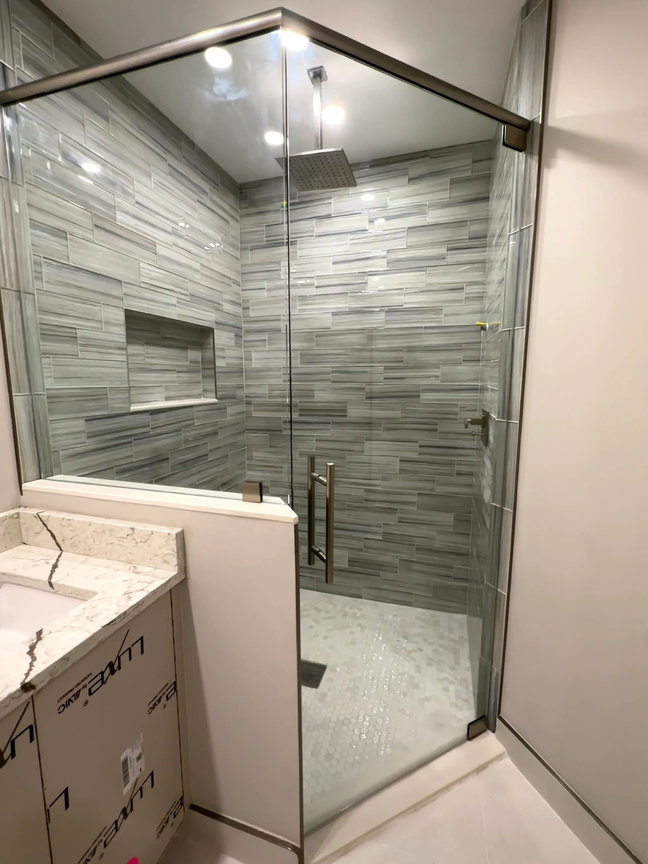 Premium glass shower enclosure with modern gray tile design. Durable, sleek, custom-made for luxury bathrooms.