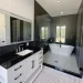 Bright bathroom with glass shower door, black and white vanity, and patterned tile flooring.