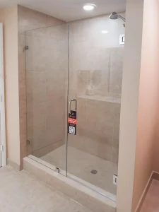 Shower glass door with sleek chrome handle and beige tiled walls.