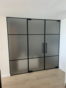 Modern frosted glass mirror closet with black frame.