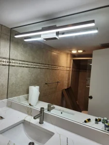High-quality custom mirror installation in a modern bathroom setting with sleek lighting.