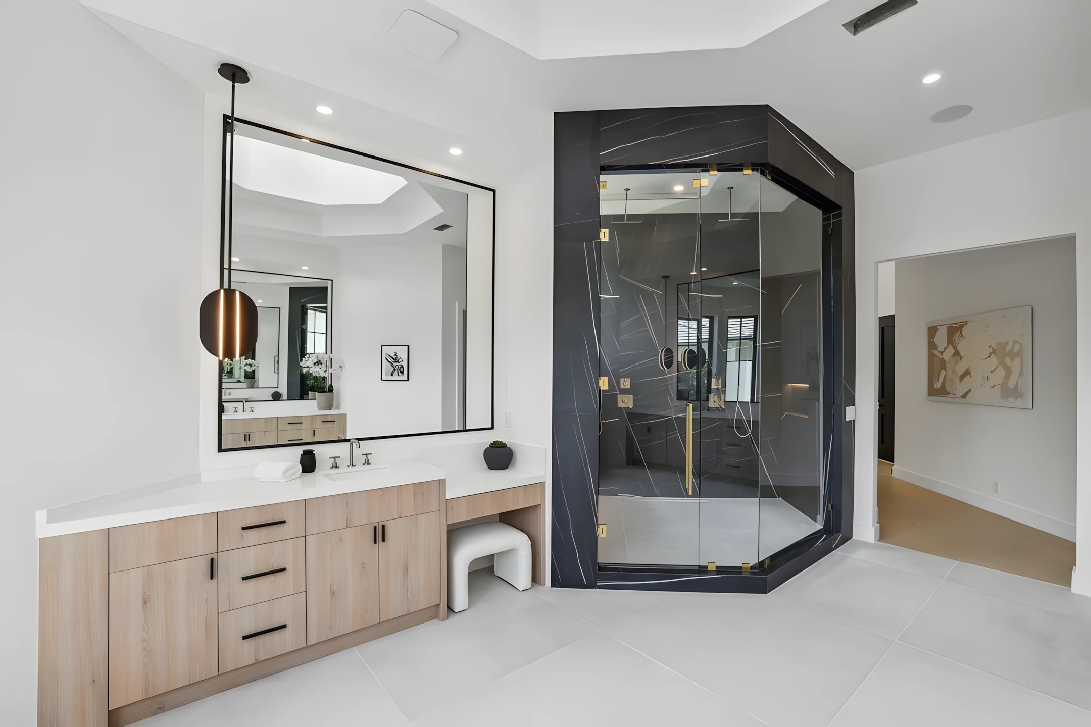Luxurious modern bathroom featuring a spacious vanity with large mirror and a sleek black marble glass shower enclosure.