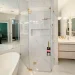 High-end glass shower with gold accents in luxurious bathroom setting.