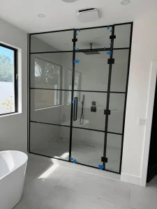 Clear glass shower door with black metal frame and handle.