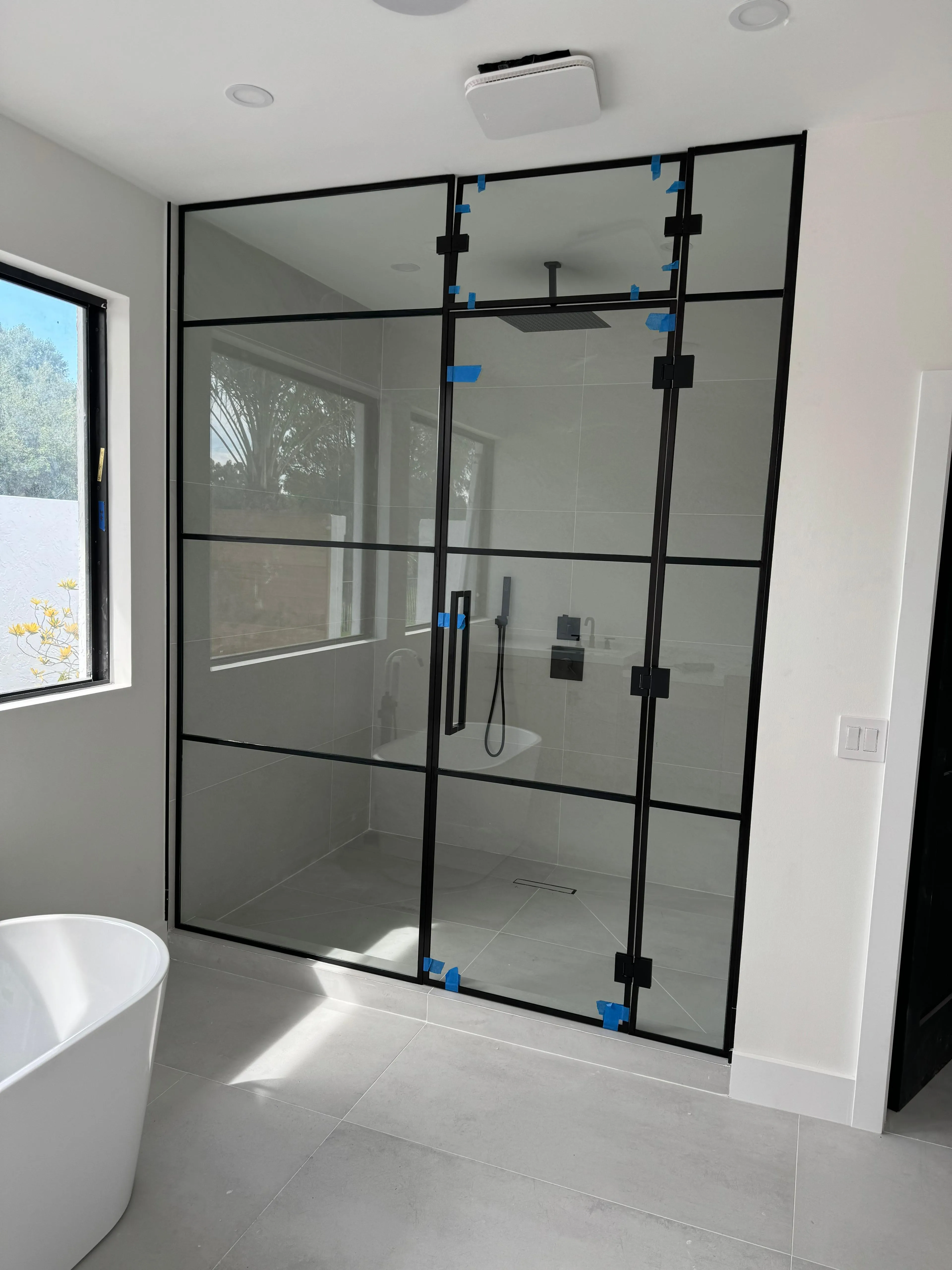 Clear glass shower door with black metal frame and handle.