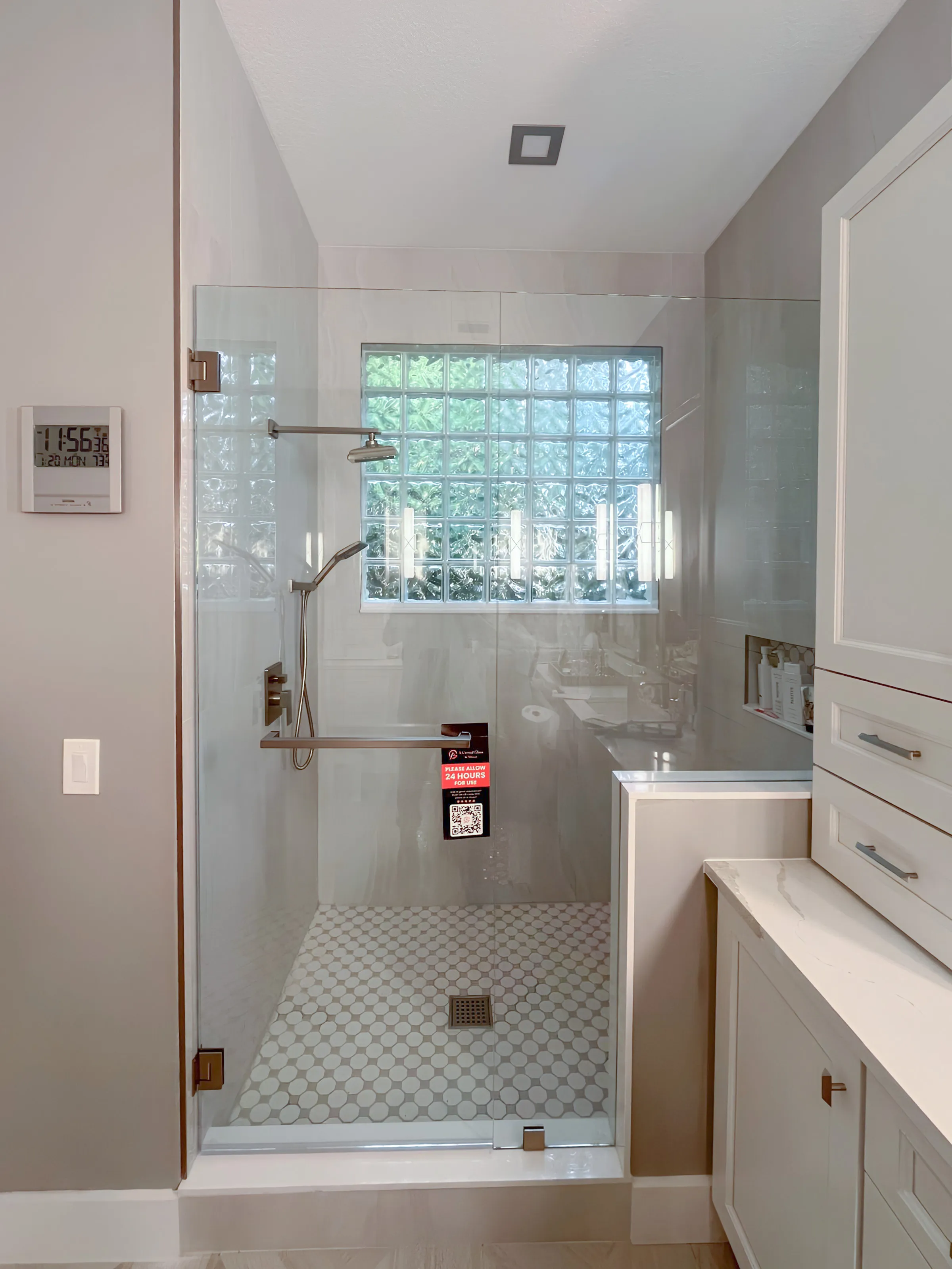 High-quality glass shower door and enclosure featuring sleek stainless steel fixtures and hex tile flooring.