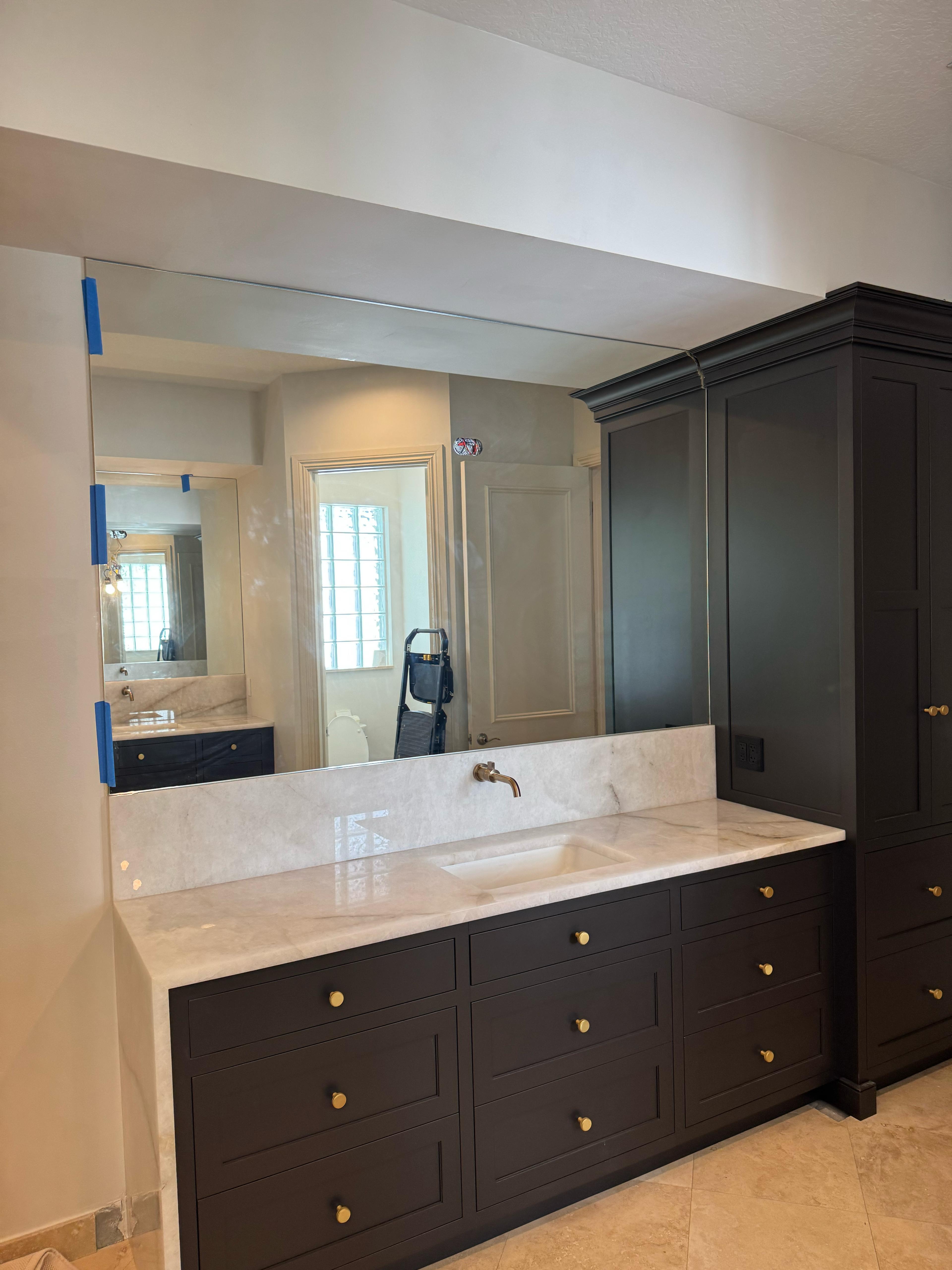Stunning bathroom mirror and black cabinetry with gold accents in a modern bathroom design.