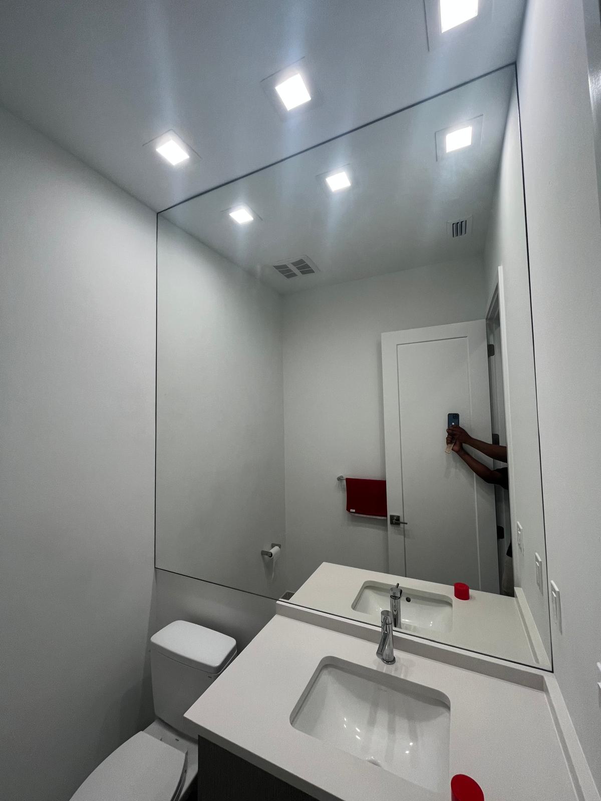 Reflective bathroom mirror with white walls and contemporary fixtures.