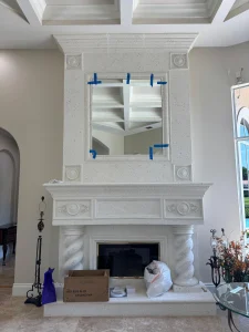 High-quality decorative mirror displayed above a classic white stone fireplace mantel. Expertly crafted for luxury interiors.